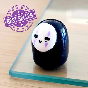 May include: A black figurine with a white face and purple markings, reminiscent of an animated character. The figurine has a glossy finish and is labelled "BEST SELLER" in a purple banner.
