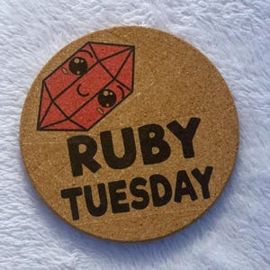 May include: A cork coaster with a red ruby gem illustration and the text "RUBY TUESDAY" in black.