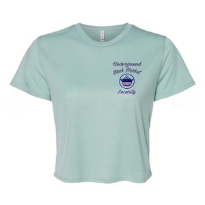 May include: A light blue cropped t-shirt with a graphic of a pot and the text "Underground Black Market Security".