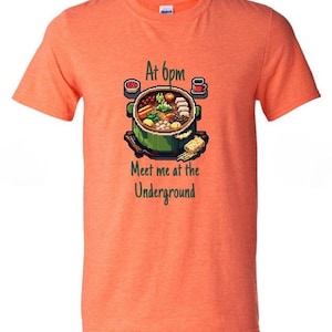 May include: Orange t-shirt with a pixelated image of a hot pot with various ingredients, a sushi roll, and a cup of coffee. The text "At 6pm Meet me at the Underground" is printed below the image.