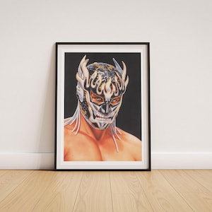 Puede incluir: Una lámina artística enmarcada que muestra el retrato de un luchador con una máscara negra, blanca y dorada con patrones de llamas y un diseño de escamas. El luchador tiene ojos azules visibles y aparece representado desde el pecho sobre fondo negro.