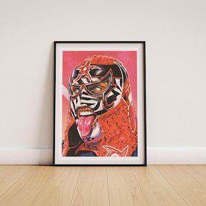 May include: A framed art print featuring a vibrant illustration of a luchador wearing a red and black mask with white zebra-like stripes. The figure has an open mouth with a visible tongue, set against a bright pink and red gradient background.