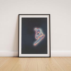 May include: Framed art print featuring a glowing, metallic figure surfing on a board against a dark, starry background. The artwork has a neon color palette with pink, blue, and purple hues, creating a futuristic and cosmic aesthetic. The print is displayed in a black frame.