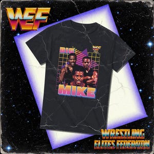 May include: Black t-shirt featuring a retro graphic of three men with the name "MIKE" in a colorful font. The shirt also displays "BIG" and the "WEF" logo, with "WRESTLING ELITES FEDERATION" text at the bottom. The design has a vintage, 80s aesthetic.