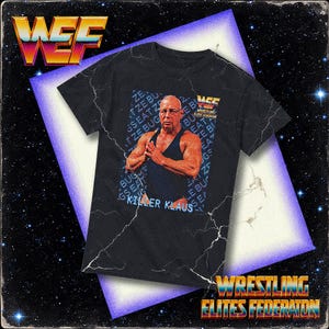 May include: Black t-shirt featuring a vintage graphic of a wrestler with the text "KILLER KLAUS". The shirt also displays the Wrestling Elites Federation logo and other text elements. The design has a retro, distressed aesthetic.