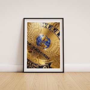 May include: A framed vertical print featuring a gold-coloured eagle emblem with spread wings centred over a blue globe. The design includes the text WORLD, HEAVYWEIGHT, and WRESTLING CHAMPION in bold lettering, set against a metallic gold background.