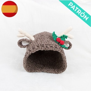 May include: A brown crocheted reindeer hat with white antlers, green holly leaves, and red berries. The hat has a hood and is designed for a child.