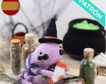 May include: A purple crocheted spider wearing a black witch hat with an orange band. The spider is holding a crocheted orange and white sock. The spider is sitting on a wooden surface with a variety of small glass bottles and a cauldron in the background.