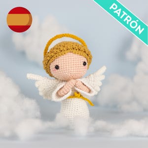 May include: A crocheted angel doll with a halo, wings, and clasped hands. The doll is mainly white with a tan face, yellow halo and accents, and pink cheeks. The word "PATRÓN" is printed on a diagonal banner. The background features fluffy white clouds.