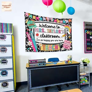 Puede incluir: Escena de aula con un tapiz que dice "Bienvenida a la clase de la Sra. Taylor". El tapiz est&aacute; decorado con ilustraciones coloridas. Tambi&eacute;n se ven un escritorio, archivadores y faroles de papel.