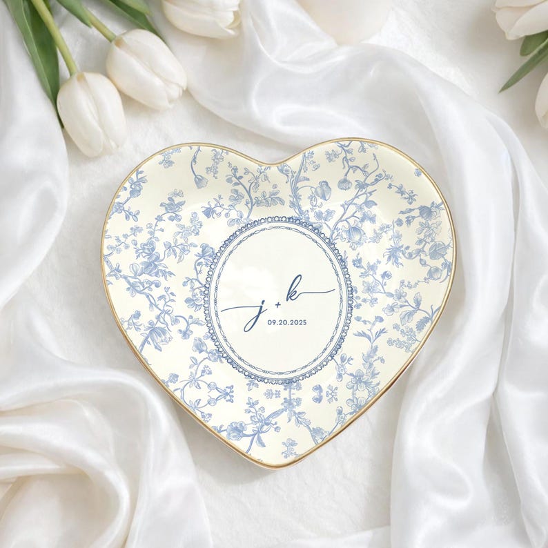 May include: Heart-shaped decorative plate with a floral blue and white design. The plate has a gold rim and a central circle with the initials "j + k" and the date "09.20.2025".