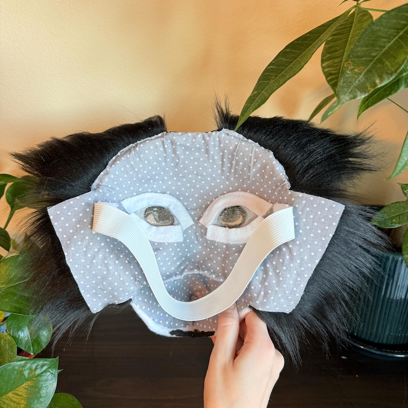 Puede incluir: Una m&aacute;scara de mono hecha a mano con una cara de lunares grises y blancos, pelo negro y correas el&aacute;sticas. La m&aacute;scara presenta recortes de ojos detallados y est&aacute; dise&ntilde;ada para uso en disfraces o cosplay.