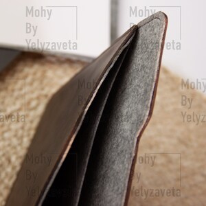 May include: A brown leather laptop sleeve with a gray felt lining. The sleeve is folded open to show the lining.