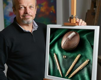 May include: A framed print of a brown football on a green velvet background with three gold pens.