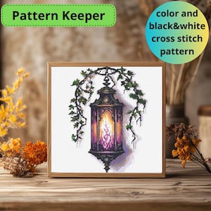 May include: A cross stitch pattern of a lantern with a purple flame hanging from a vine. The pattern is available in color and black and white.