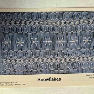 May include: A printed pattern titled "Snowflakes" with a blue background and white snowflake and geometric designs. The text "COPYRIGHT IN USA MOLLIE JANE TAYLOR, 1981" is visible. The designer is Peggy Panton, and it was printed in the USA.