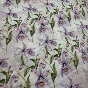 Może przedstawiać: Tkanina z powtarzającym się wzorem fioletowych kwiatów orchidei i zielonych liści na jasnoniebieskim tle. Orchidee mają szczegółowe płatki i żółty środek. Projekt jest w stylu akwareli.