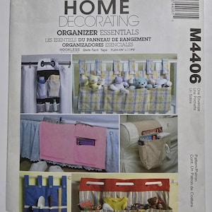 Può includere: Modello McCall's Home Decorating con vari elementi essenziali per l'organizzazione. L'immagine mostra esempi di organizzatori in tessuto, tra cui contenitori sospesi per armadi e culle. Il modello include istruzioni per creare questi articoli.