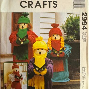 May include: McCall's Crafts sewing pattern envelope featuring three snowman figures in festive attire. The snowmen wear colorful coats, hats, and scarves, holding holly. The envelope includes the number 2994 and the text "One Envelope".