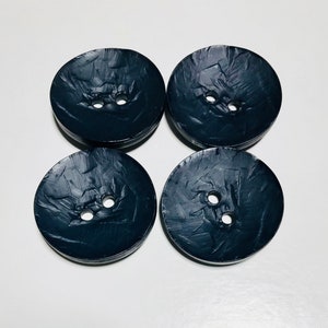 May include: Four black plastic buttons with a textured surface and two holes each.