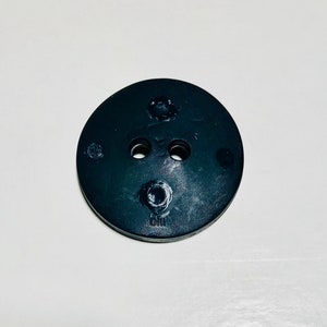 May include: Black rubber washer with two holes and a small raised circle in the center. The washer has the letters "GM" embossed on the bottom.
