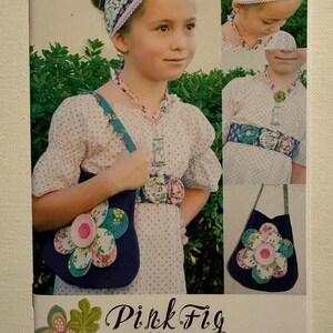 May include: A young person wearing a floral headband, necklace, and belt, along with a navy blue purse with a large flower design. The outfit is part of the "Pink Fig patterns Accessories no. 24" collection.
