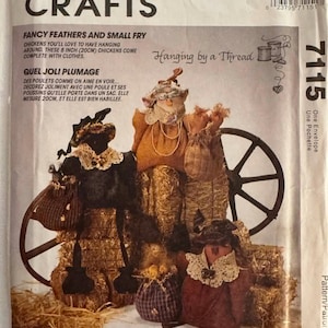 Op de afbeelding: McCall's Crafts patroon voor het maken van decoratieve kippen. Het patroon bevat instructies voor het maken van kippen van 20 cm hoog, compleet met kleding. De afbeelding toont de afgewerkte kippen met stro en een wagenwiel.