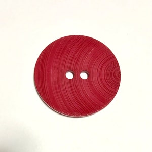 May include: A red button with a woodgrain pattern and two holes.