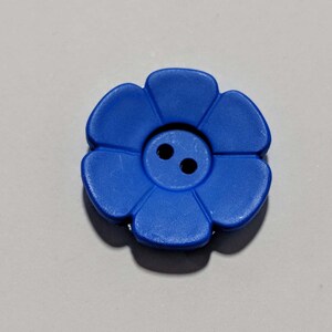 May include: A blue plastic flower-shaped button with two holes in the center.