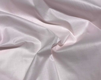 May include: A smooth, pale pink fabric with a subtle sheen. The fabric is draped and folded, showcasing its soft texture.