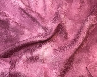May include: A pink fabric with a white and pink patterned design. The fabric is wrinkled and has a soft, silky texture.