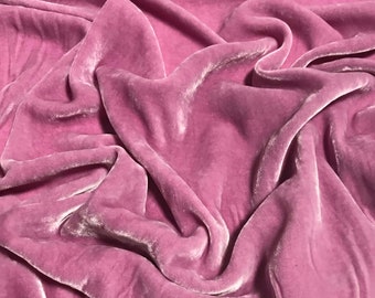 May include: A close-up of a soft, pink velvet fabric with a smooth, silky texture. The fabric is draped and folded, creating a luxurious and elegant look.