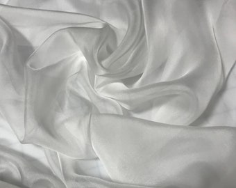 May include: White sheer fabric with a smooth, silky texture. The fabric is draped and folded, creating soft, flowing lines.