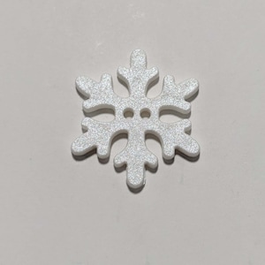 May include: A white snowflake-shaped wooden button with a glittery finish.