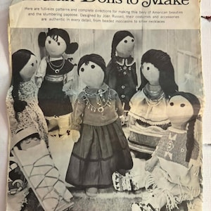 May include: A vintage magazine page titled Indian Dolls to Make featuring instructions and patterns for handmade fabric dolls. The page displays six dolls with dark hair, wearing detailed outfits including beaded moccasins and silver necklaces.