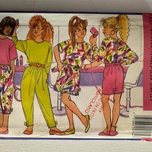 May include: A Butterick Busybodies sewing pattern envelope 4944 for sizes 7-8-10, featuring illustrations of four figures in 1980s-style clothing, including a pink top with patterned trousers, a lime green jumpsuit, and patterned skirt sets.