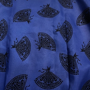 Könnte beinhalten: Blauer Stoff mit einem sich wiederholenden Muster aus schwarzen, stilisierten Fächer. Die Fächer sind mit komplizierten Designs verziert und ähneln einem Kleid.