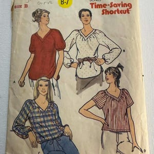 May include: Vintage Butterick sewing pattern featuring four blouse designs. The pattern includes illustrations of blouses with various sleeve lengths and patterns, including stripes, polka dots, and plaid. The pattern is labeled size B and includes the text "Time-Saving Shortcut".