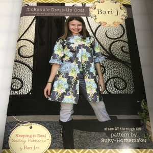 May include: A sewing pattern for a dress-up coat called "Mckenzie Dress-Up Coat" by Bari J. The pattern includes three-quarter and long sleeve options. The pattern is for sizes 2T through 6/8 and is designed by Suzy-Homemaker.