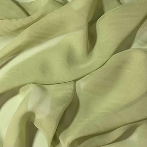 May include: A piece of light green sheer fabric with a soft, flowing texture. The fabric is draped and folded, creating a sense of movement and lightness.