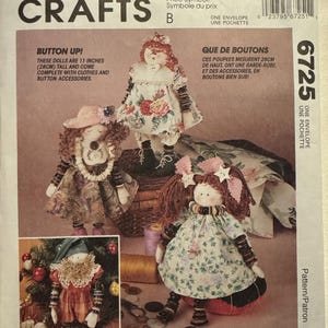 May include: McCall's Crafts pattern for Button Up! dolls, 11 inches tall, with clothes and button accessories. The image shows three finished dolls in floral dresses and hats, with button details. The pattern includes the text "Button Up!"