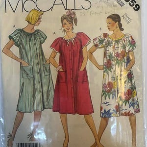 May include: A vintage McCall's sewing pattern packet featuring illustrations of three different dresses. The dresses are in green stripes, red, and a floral print. The packet includes the number 2559 and the words "SMALL PETITE".