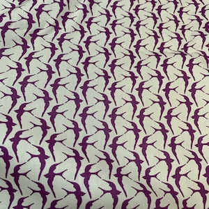 May include: A white fabric with a repeating pattern of purple birds. The birds are all facing the same direction and are in a staggered pattern.