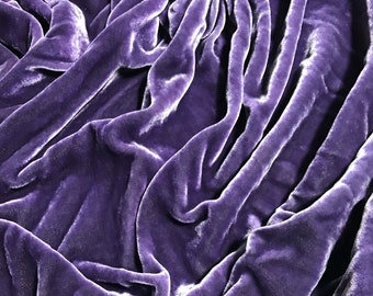 May include: Close-up of a deep purple velvet fabric with a soft, smooth texture. The fabric is draped and folded, creating a luxurious and elegant look.