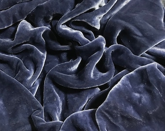 May include: Close-up of a deep blue velvet fabric with a soft, smooth texture. The fabric is draped and folded, creating a luxurious and elegant look.