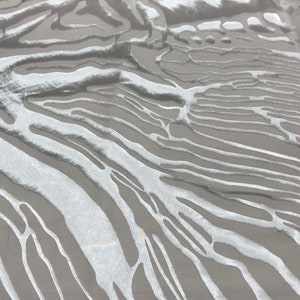 May include: Abstract pattern of white lines on a grey background. The lines are wavy and organic, creating a flowing and dynamic design.
