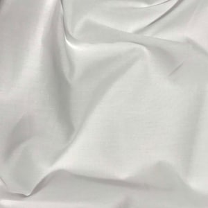 May include: White fabric with a smooth, silky texture. The fabric is draped and folded, creating soft, flowing lines.