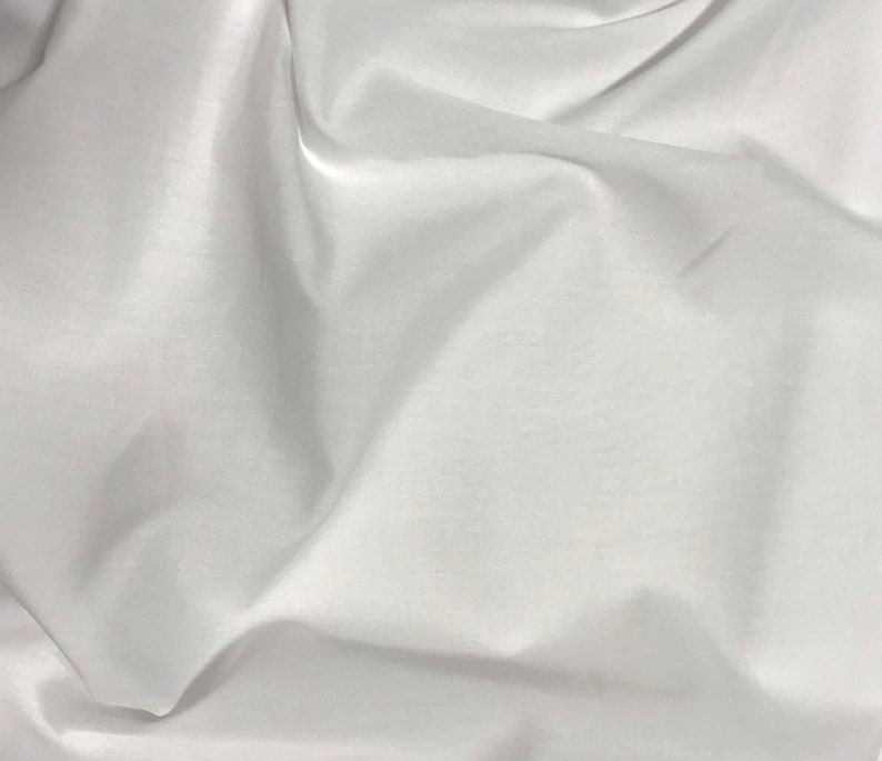 Puede incluir: Tela blanca con una textura suave y sedosa. La tela est&aacute; drapeada y doblada, creando l&iacute;neas suaves y fluidas.