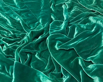 May include: A close-up of a deep green velvet fabric, showcasing the soft texture and drape of the material.