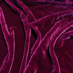 May include: Close-up of a deep purple velvet fabric with soft, flowing folds and a luxurious texture.